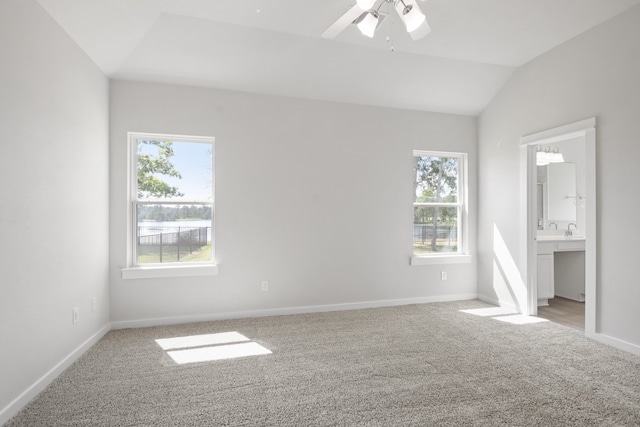 unfurnished bedroom featuring multiple windows, connected bathroom, vaulted ceiling, and ceiling fan