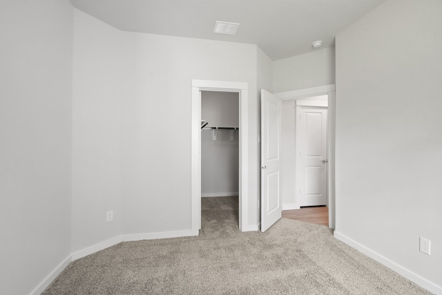 unfurnished bedroom with a spacious closet and carpet floors