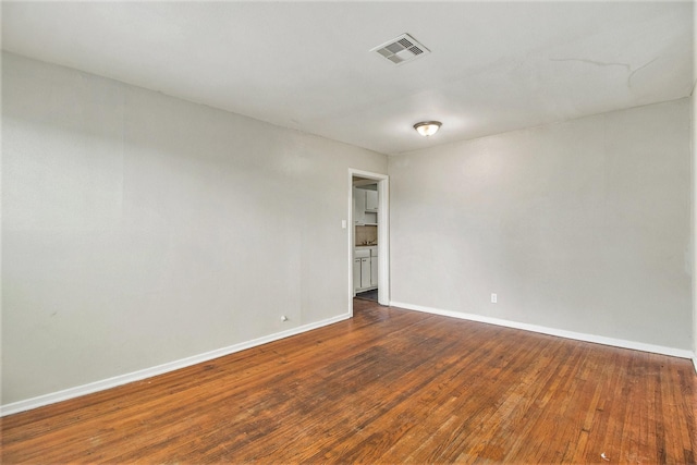 spare room with hardwood / wood-style floors, baseboards, and visible vents