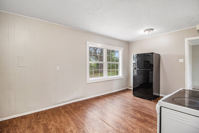 kitchen with black fridge, white electric stove, hardwood / wood-style flooring, and a textured ceiling