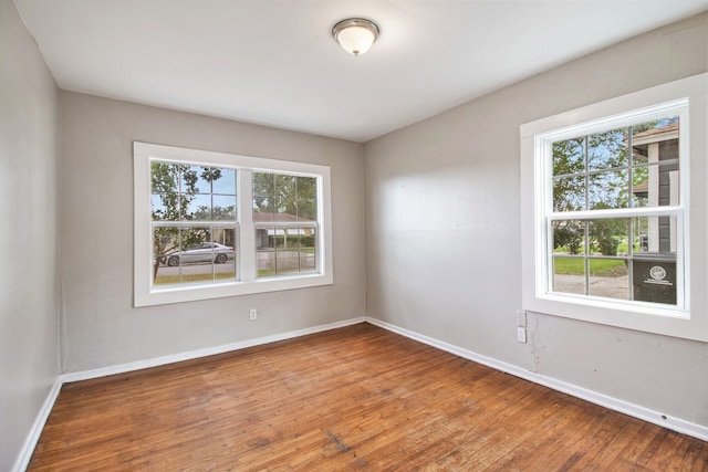 spare room with a wealth of natural light and hardwood / wood-style floors