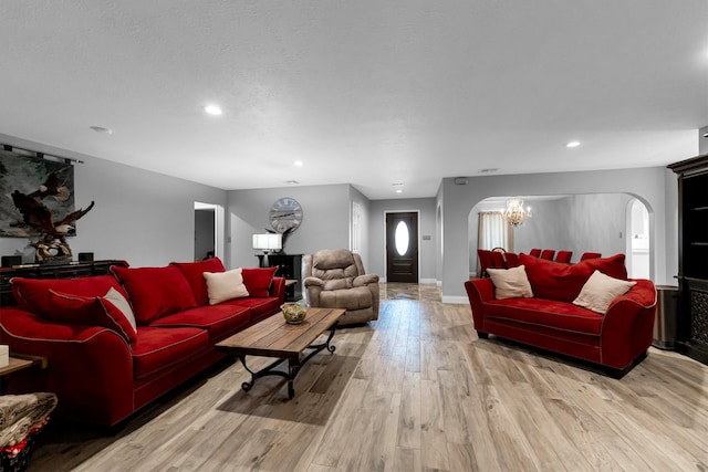 living room featuring light wood-type flooring, a notable chandelier, and a textured ceiling