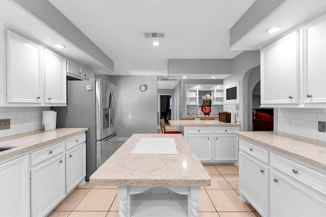 kitchen featuring a center island, decorative backsplash, white cabinetry, and light tile patterned flooring