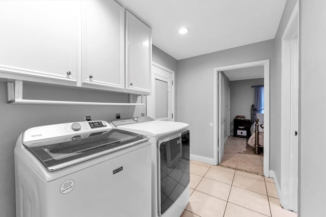 laundry room with light tile patterned floors, independent washer and dryer, and cabinets