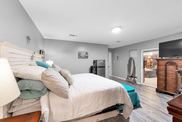 bedroom featuring stainless steel fridge and hardwood / wood-style flooring