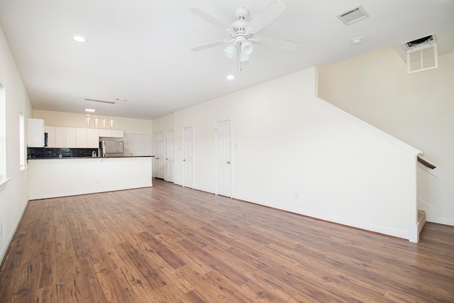 unfurnished living room featuring dark wood-type flooring and ceiling fan