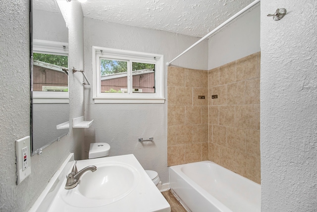 full bathroom with toilet, tiled shower / bath, a textured ceiling, wood-type flooring, and sink