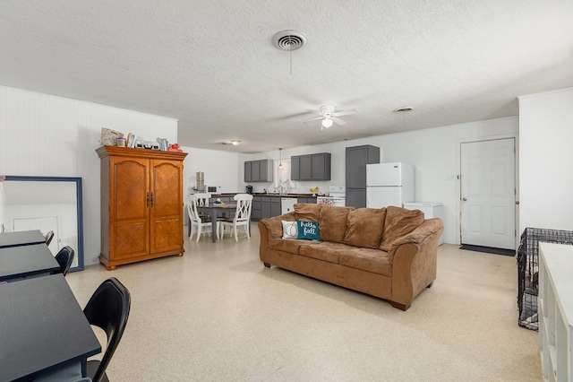 living room with a textured ceiling and ceiling fan