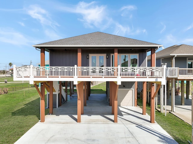 back of house featuring covered porch, a carport, a garage, and a lawn