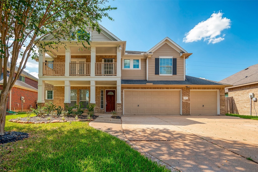 view of front of property featuring a front yard, a balcony, and a garage