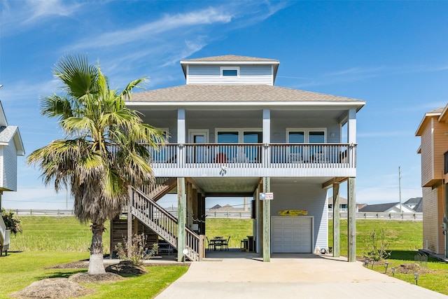 coastal inspired home featuring covered porch, a front yard, and a garage