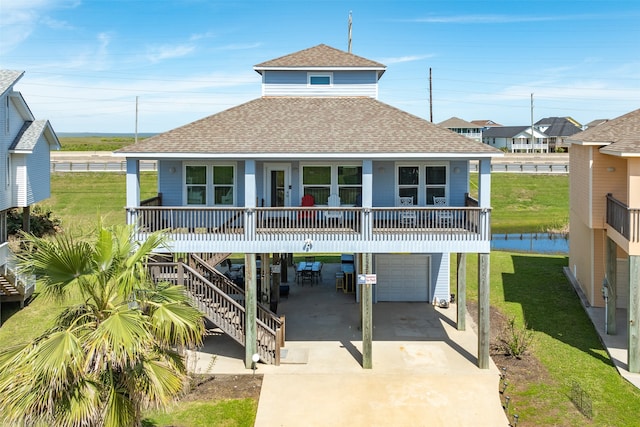 raised beach house with a carport, a garage, a front yard, and covered porch