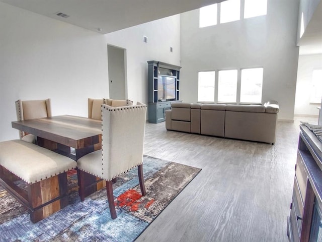 dining area featuring wood-type flooring and a high ceiling