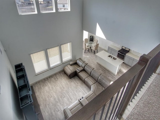 living room featuring light wood-type flooring, sink, and a high ceiling