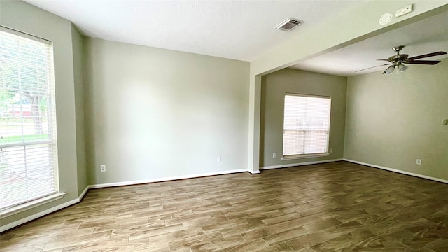 spare room featuring a wealth of natural light, hardwood / wood-style floors, and ceiling fan