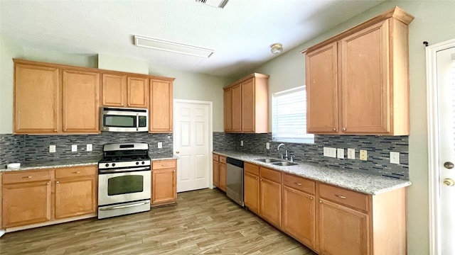 kitchen featuring light hardwood / wood-style flooring, stainless steel appliances, sink, and decorative backsplash