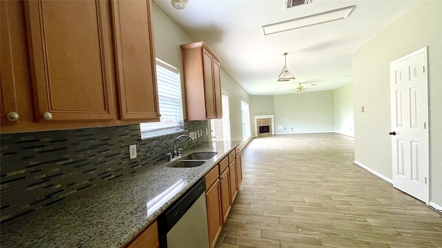 kitchen with tasteful backsplash, light hardwood / wood-style flooring, dishwasher, light stone counters, and sink