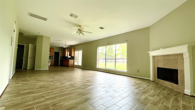 unfurnished living room with light hardwood / wood-style flooring, ceiling fan, and a tile fireplace