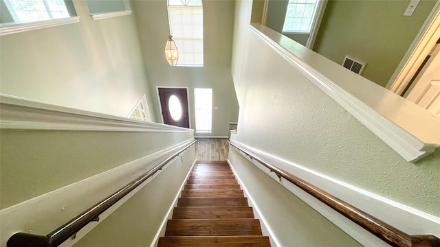 stairs with a wealth of natural light and hardwood / wood-style flooring