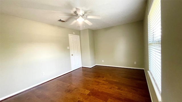 unfurnished room with a wealth of natural light, ceiling fan, and dark hardwood / wood-style flooring