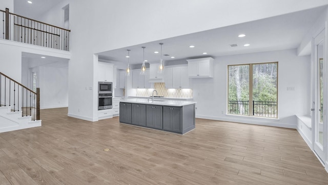 kitchen with built in microwave, white cabinets, light wood finished floors, and stainless steel oven