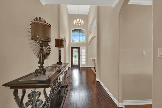 foyer entrance with french doors, an inviting chandelier, crown molding, a towering ceiling, and dark hardwood / wood-style flooring