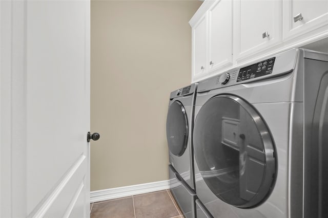 clothes washing area with dark tile patterned floors, cabinets, and separate washer and dryer