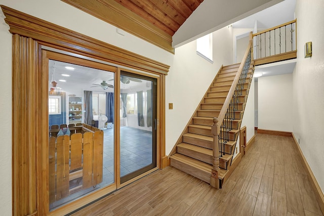 stairs with ceiling fan, wood ceiling, and lofted ceiling