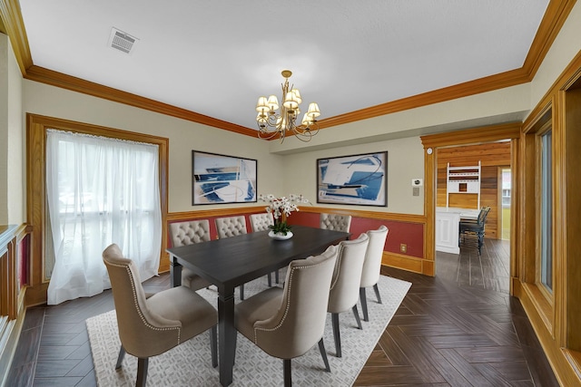 dining area with dark parquet flooring, crown molding, and an inviting chandelier