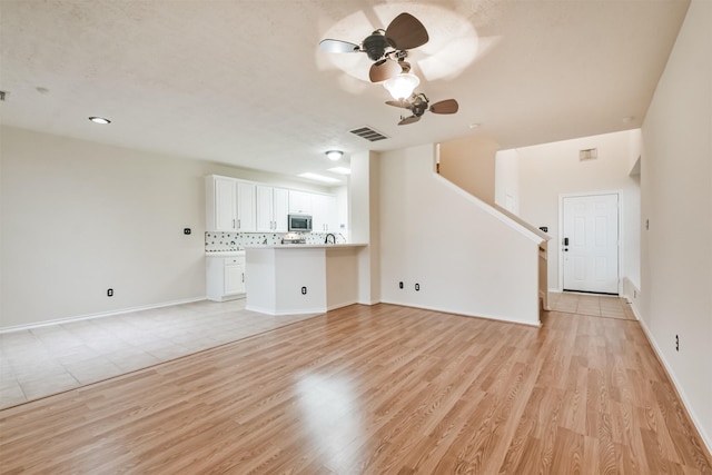 unfurnished living room featuring a ceiling fan, light wood-type flooring, visible vents, and baseboards