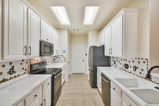 kitchen with stainless steel appliances, white cabinets, a sink, and light tile patterned flooring