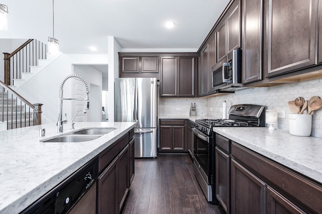 kitchen featuring hanging light fixtures, stainless steel appliances, sink, dark brown cabinets, and dark wood-type flooring