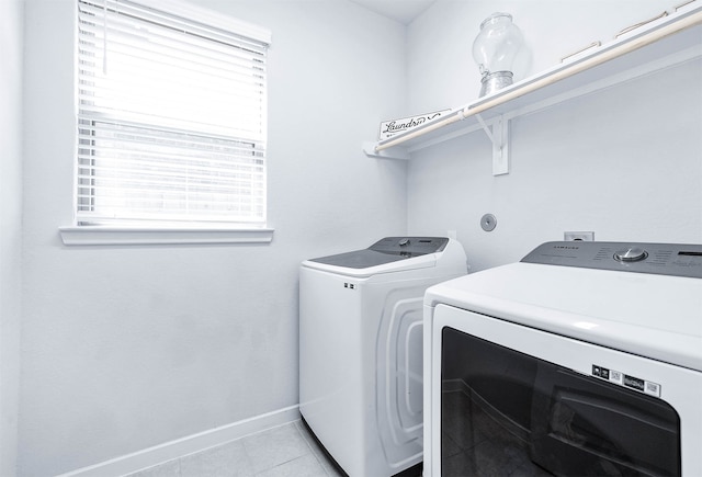 clothes washing area featuring a healthy amount of sunlight, washer and clothes dryer, and light tile patterned flooring