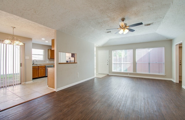 unfurnished living room featuring ceiling fan with notable chandelier, a textured ceiling, light hardwood / wood-style flooring, and sink