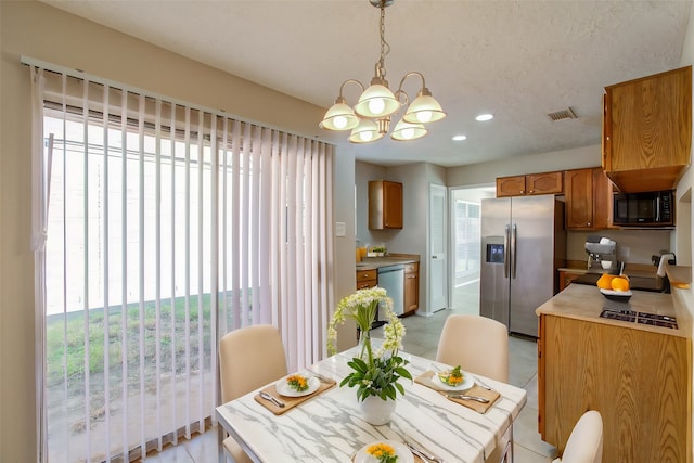 dining space with a textured ceiling, plenty of natural light, an inviting chandelier, and light tile patterned floors