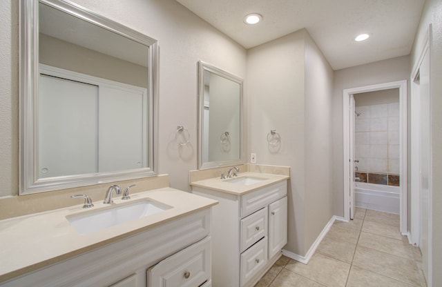 bathroom with a textured ceiling, vanity, tiled shower / bath combo, and tile patterned floors