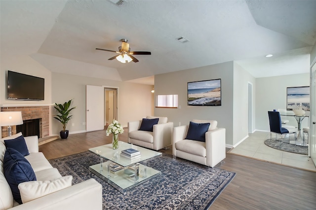 living room featuring hardwood / wood-style floors, ceiling fan, and a brick fireplace