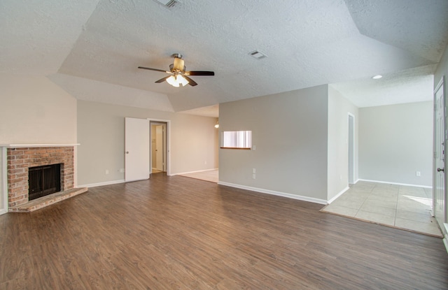 unfurnished living room with wood-type flooring, a fireplace, a textured ceiling, and ceiling fan