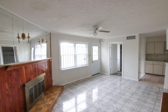 unfurnished living room with ornamental molding, a textured ceiling, and ceiling fan