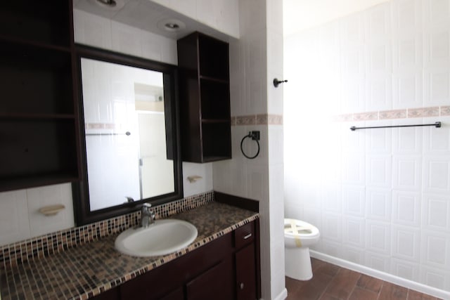 bathroom featuring tile walls, wood-type flooring, toilet, and vanity