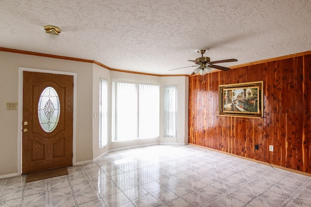 foyer entrance featuring a textured ceiling, wood walls, and ceiling fan