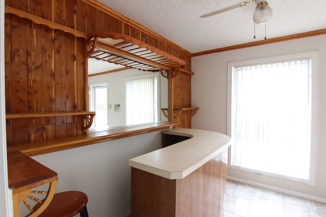 kitchen with ornamental molding, a textured ceiling, a wealth of natural light, and kitchen peninsula