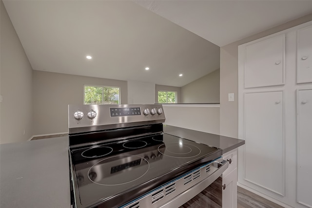 kitchen featuring vaulted ceiling, white cabinetry, electric stove, and light hardwood / wood-style floors