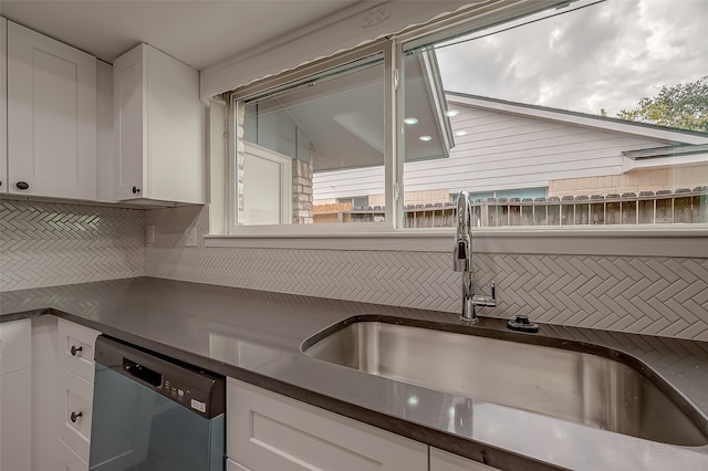 kitchen featuring a wealth of natural light, stainless steel dishwasher, sink, and white cabinetry