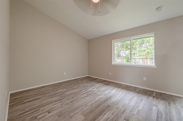 spare room featuring ceiling fan, light wood-type flooring, and vaulted ceiling