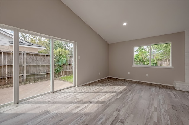 spare room featuring a wealth of natural light, light hardwood / wood-style flooring, and high vaulted ceiling