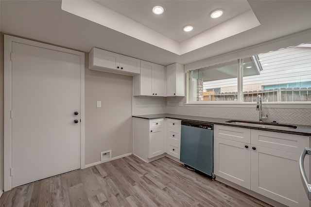 kitchen with a tray ceiling, dishwasher, white cabinetry, and light hardwood / wood-style flooring