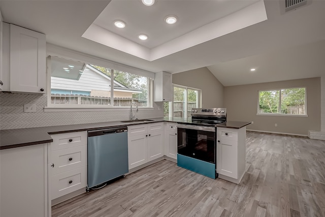 kitchen with appliances with stainless steel finishes, light hardwood / wood-style floors, kitchen peninsula, sink, and white cabinets