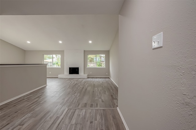 unfurnished living room with lofted ceiling, light hardwood / wood-style floors, and a fireplace