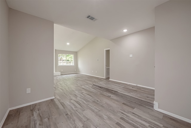 empty room with light hardwood / wood-style flooring and vaulted ceiling